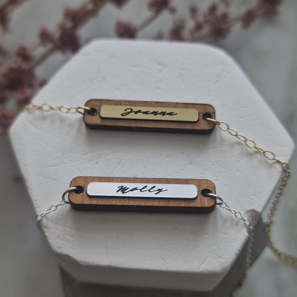 Video showing two personalised necklaces in silver and gold etched with names