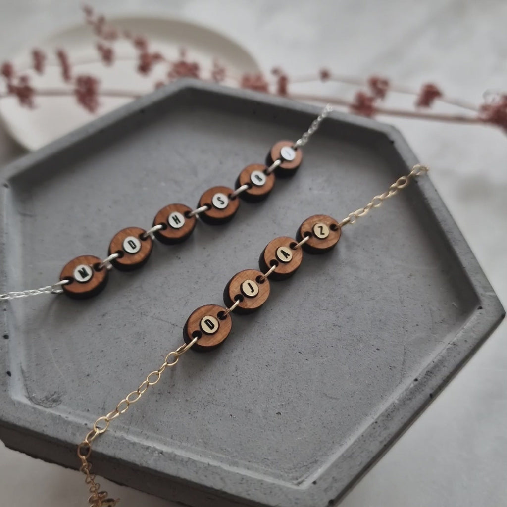 video showing two wood bead necklaces in silver and gold, both engraved with initials